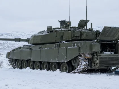 Broken-down British tank in snowy terrain with an open engine compartment for maintenance.